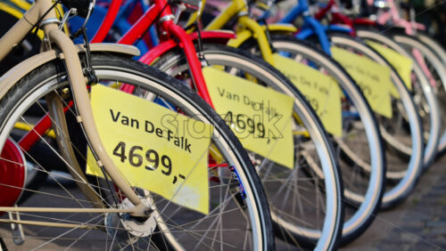 Video - Copenhagen, Denmark - August 6, 2025: Bicycles in various colors lined up on a cobblestone street with yellow price tags