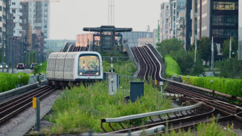 Video - Copenhagen, Denmark - August 6, 2025: Metro train traveling on rails through a green urban environment in a modern city