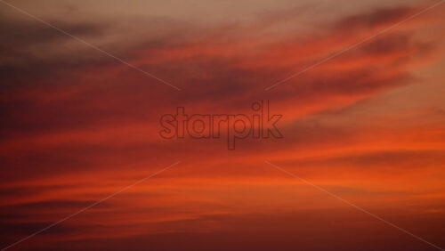 Video - Sunset clouds creating a gradient of fiery red, orange, and golden hues across the sky