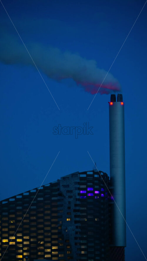 Video - Copenhill waste to energy plant with an architectural facade and illuminated windows at night. Copenhagen, Denmark