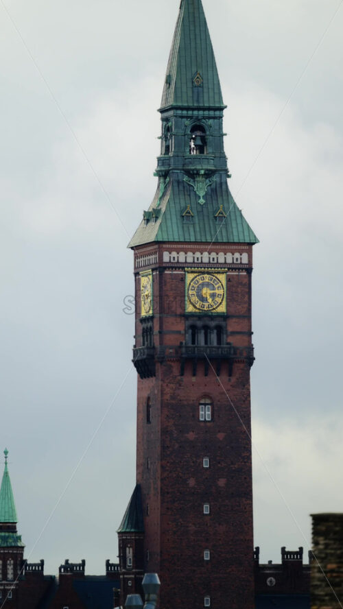 Video - Ornate clock tower of Copenhagen City Hall reaching into a gray sky over rooftops