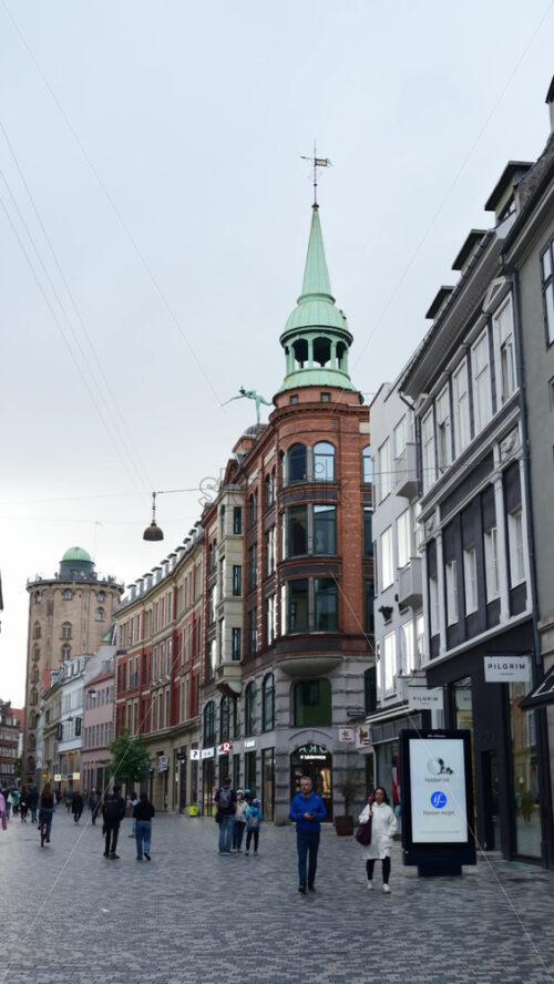 Video - Copenhagen, Denmark - August 7, 2025: People walking along a pedestrian street featuring historic architecture and shops during daytime