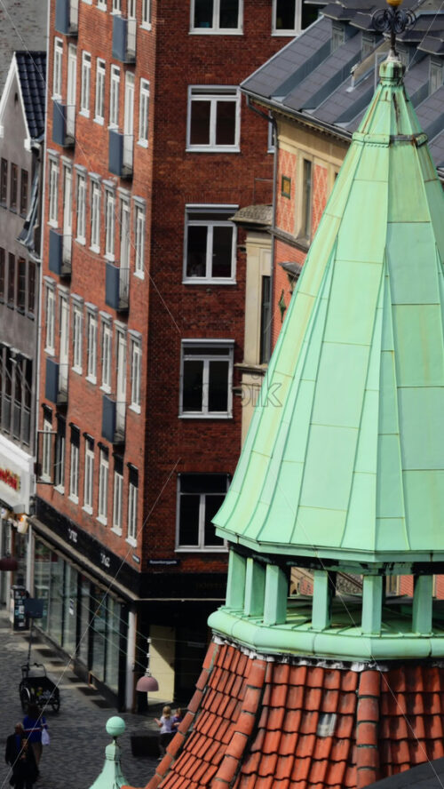 Video - Copenhagen, Denmark - August 7, 2025: Building rooftop view showing a weathered green copper spire and terracotta tiles