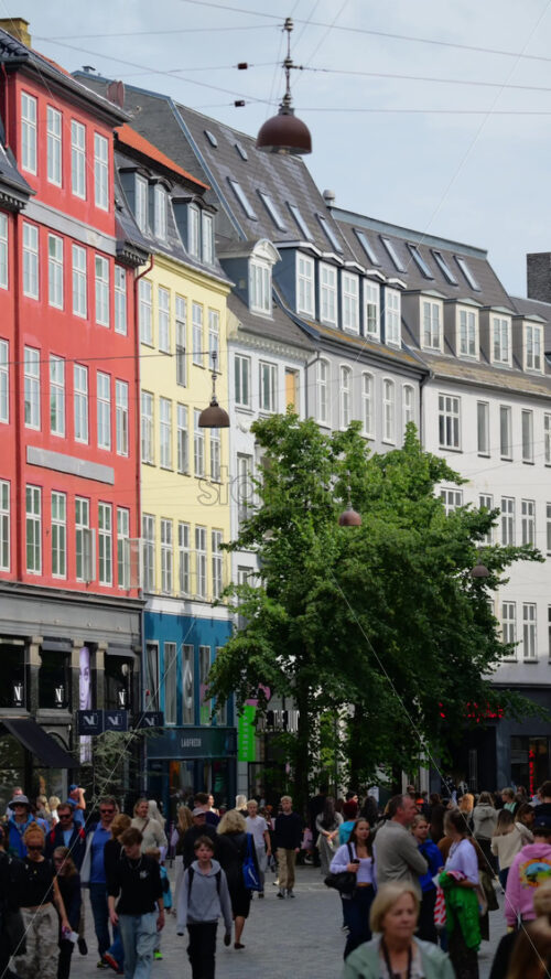 Video - Copenhagen, Denmark - August 7, 2025: People walking on a busy European shopping street with historic architecture under a cloudy sky