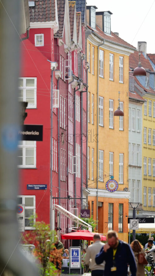 Video - Copenhagen, Denmark - August 7, 2025: Colorful old buildings lining a street with people enjoying outdoor cafe seating