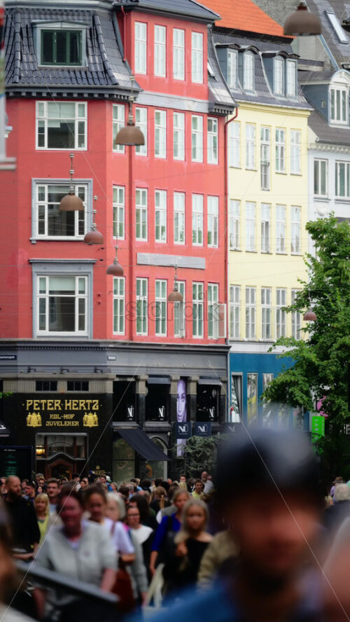Video - Copenhagen, Denmark - August 7, 2025: Crowds of people walking along Amagertorv street past colorful buildings and shops