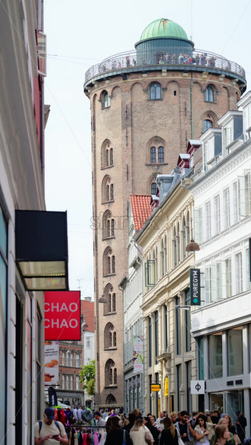 Video - Copenhagen, Denmark - August 7, 2025: Rundetaarn, a historic observatory, standing tall above a busy shopping street filled with people