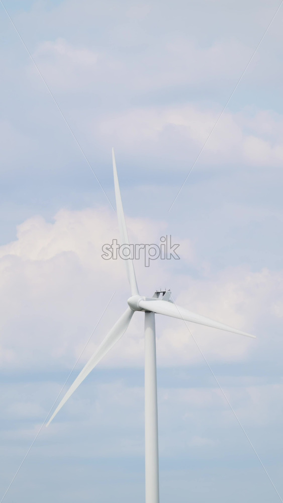 Video - Copenhagen, Denmark - August 7, 2025: Wind turbine standing under a light cloudy sky, generating electricity