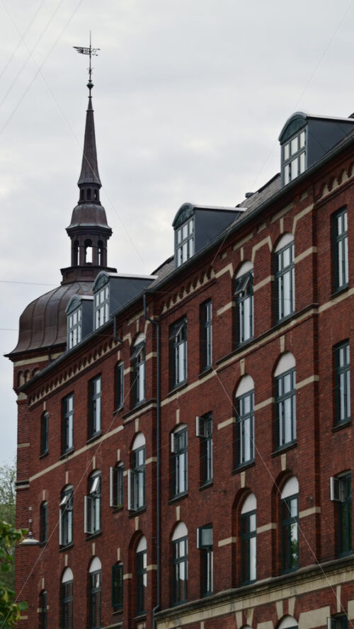 Video - Traditional brick building featuring a classic spire and elegant dormer windows under a cloudy sky. Copenhagen, Denmark