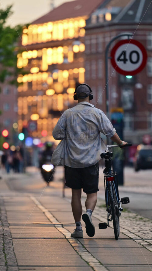 Video - Person walking a bicycle on an urban sidewalk during sunset, enjoying sustainable urban mobility. Copenhagen, Denmark