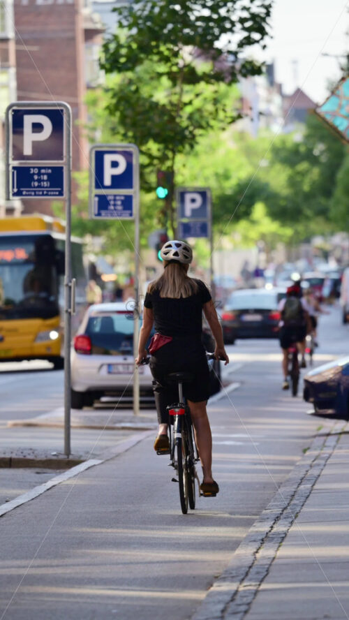 Video - Copenhagen, Denmark - August 7, 2025: Cyclist riding a bike on a busy street with traffic and parking signs