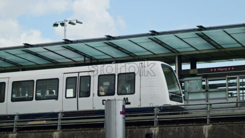 Video - Copenhagen, Denmark - August 4, 2025: Driverless Metro train arriving at an elevated station platform under a modern glass roof