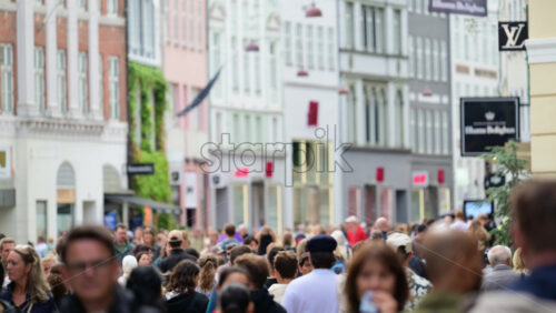 Video - Copenhagen, Denmark - August 2, 2025: People walking on a busy street in the old center with blurred store fronts and buildings