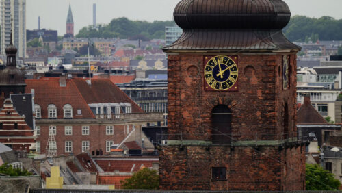 Video - Old brick church clock tower rising above traditional red roof buildings in Copenhagen, Denmark