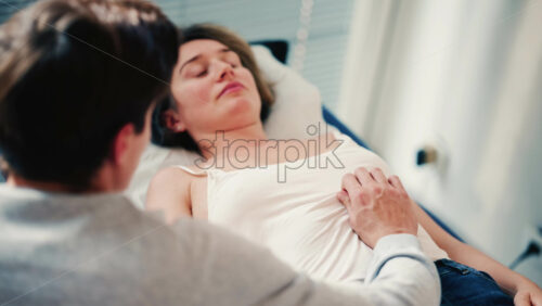 Video - Therapist examines a woman lying on a medical bed, placing hands on the abdomen as part of an assessment or treatment