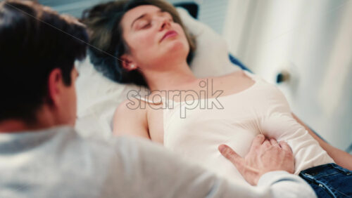 Video - Therapist examines a woman lying on a medical bed, placing hands on the abdomen as part of an assessment or treatment