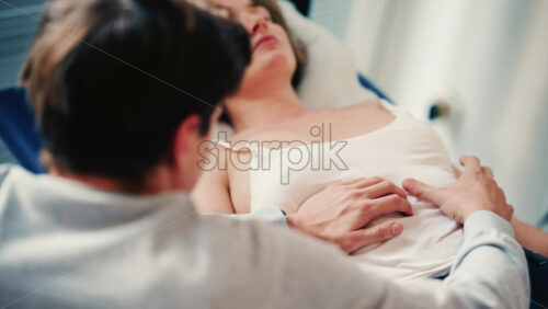 Video - Therapist examines a woman lying on a medical bed, placing hands on the abdomen as part of an assessment or treatment