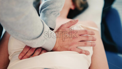 Video - Close up of a practitioner's hands applying gentle pressure on a patient's torso during a hands-on therapy session