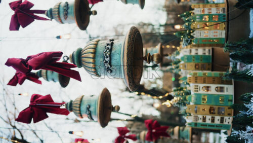 Video - Decorative hanging bells with red bows and warm string lights outdoors. Vertical
