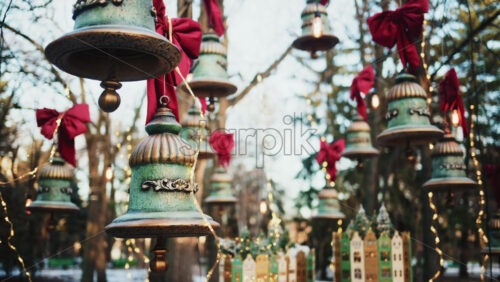 Video - Decorative hanging bells with red bows and warm string lights outdoors