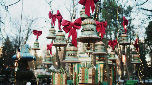 Video - Decorative hanging bells with red bows and warm string lights outdoors