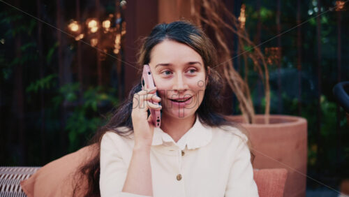 Video - Woman sitting outdoors while talking on a smartphone, looking thoughtful