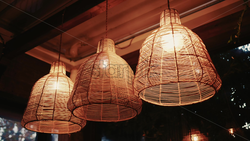 Video - Decorative wicker lamps hanging indoors with warm light with a cozy and stylish interior atmosphere