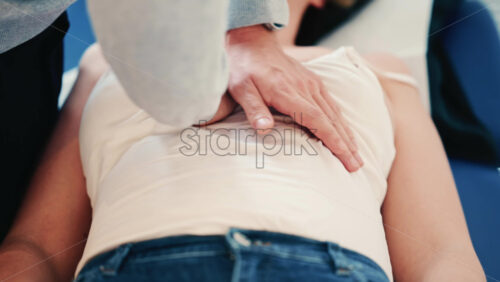 Video - Close up of a practitioner's hands applying gentle pressure on a patient's torso during a hands-on therapy session