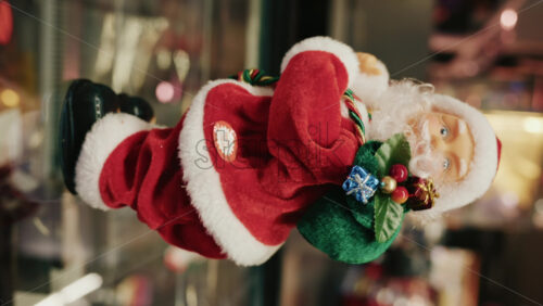 Video - Santa Claus figurine holding a green gift bag decorated with small presents, moving. Vertical
