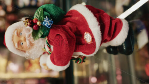 Video - Santa Claus figurine holding a green gift bag decorated with small presents, moving. Vertical