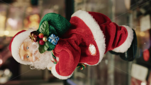 Video - Santa Claus figurine holding a green gift bag decorated with small presents, moving. Vertical