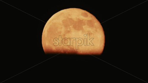Video - Large full moon rising against a dark night sky with clear details and dramatic atmosphere