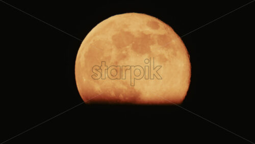 Video - Large full moon rising against a dark night sky with clear details and dramatic atmosphere