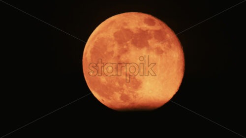 Video - Large full moon rising against a dark night sky with clear details and dramatic atmosphere