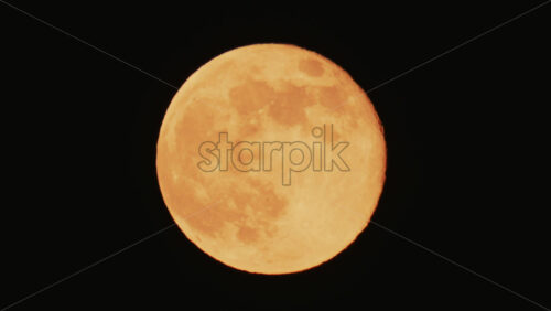 Video - Large full moon rising against a dark night sky with clear details and dramatic atmosphere