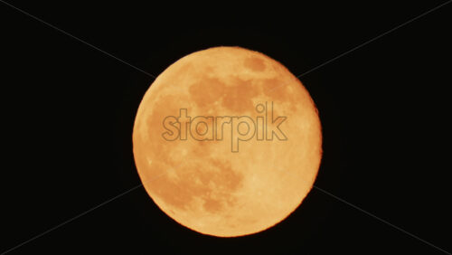 Video - Large full moon rising against a dark night sky with clear details and dramatic atmosphere