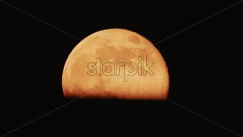 Video - Large full moon rising against a dark night sky with clear details and dramatic atmosphere