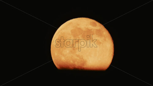 Video - Large full moon rising against a dark night sky with clear details and dramatic atmosphere