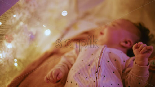 Video - Close up of a baby with a pacifier illuminated by warm Christmas lights, creating a joyful and heartwarming holiday mood