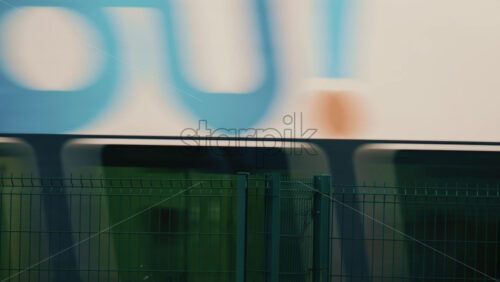 Video - Abstract shot of a high speed train passing behind a metal fence, creating motion blur and geometric line