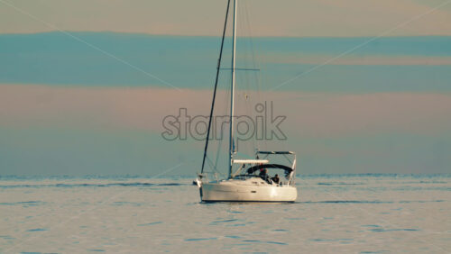 Video - Wide shot of sailboats anchored on calm open water with distant shoreline in the background