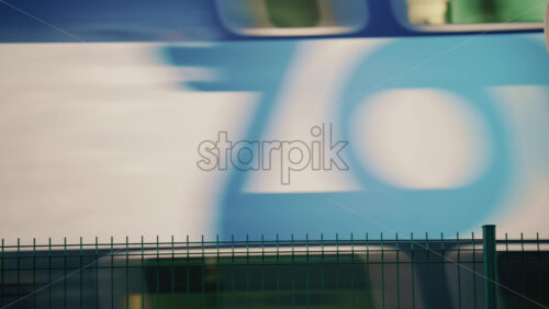 Video - A high speed train passing behind a metal fence, creating motion blur and geometric line