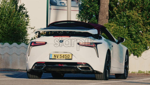 Video - Antibes, France - December 17, 2025: Rear view of a white Lexus convertible car with soft top roof opening while parked outdoors