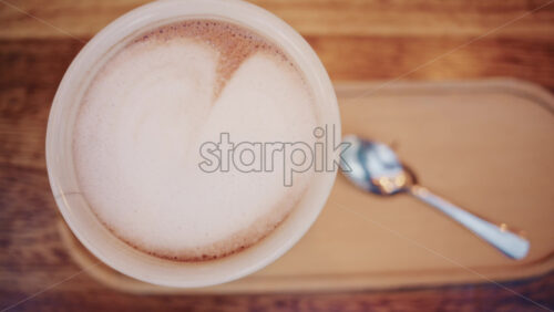 Video - Top down view of a cappuccino with creamy milk foam served on a wooden table