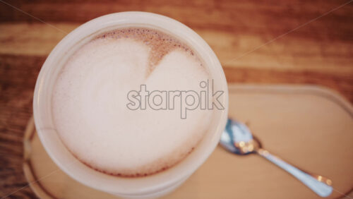 Video - Top down view of a cappuccino with creamy milk foam served on a wooden table
