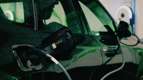 Video - Close up view of a black electric car plugged into a charging station
