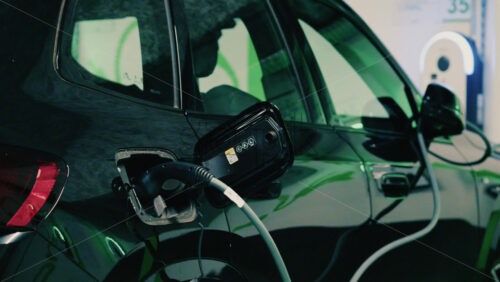 Video - Close up view of a black electric car plugged into a charging station