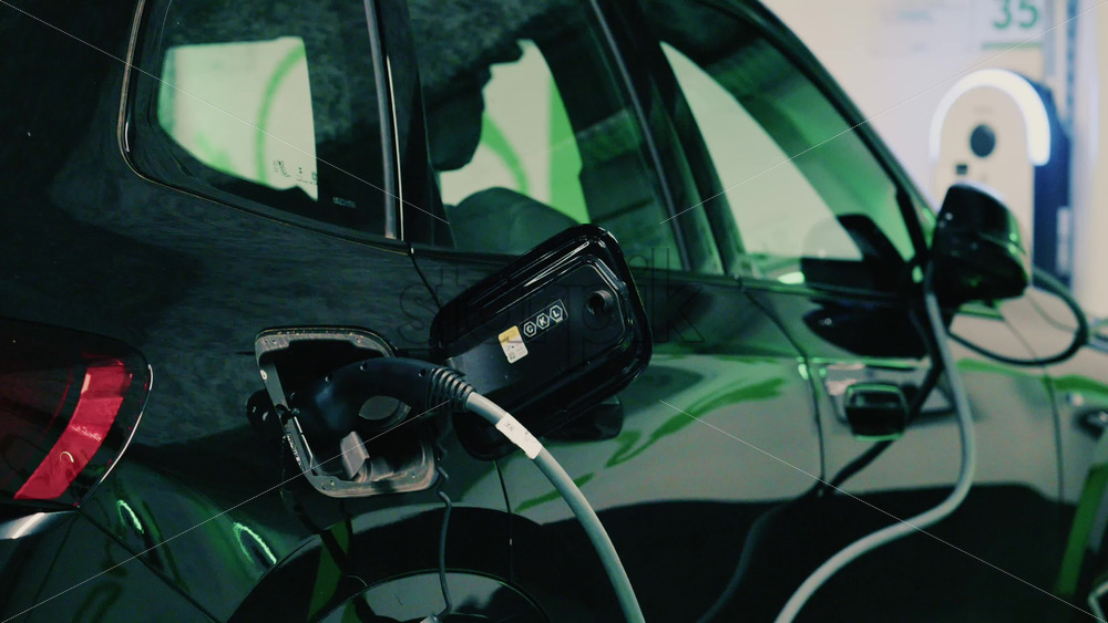 Video - Close up view of a black electric car plugged into a charging station