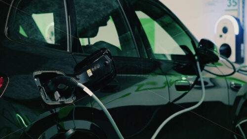 Video - Close up view of a black electric car plugged into a charging station