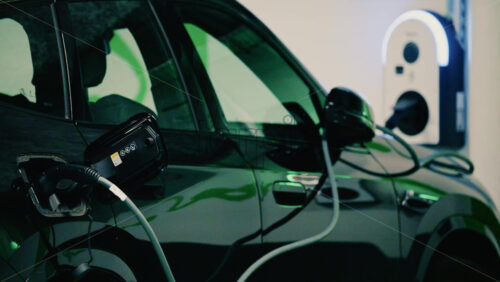 Video - Close up view of a black electric car plugged into a charging station